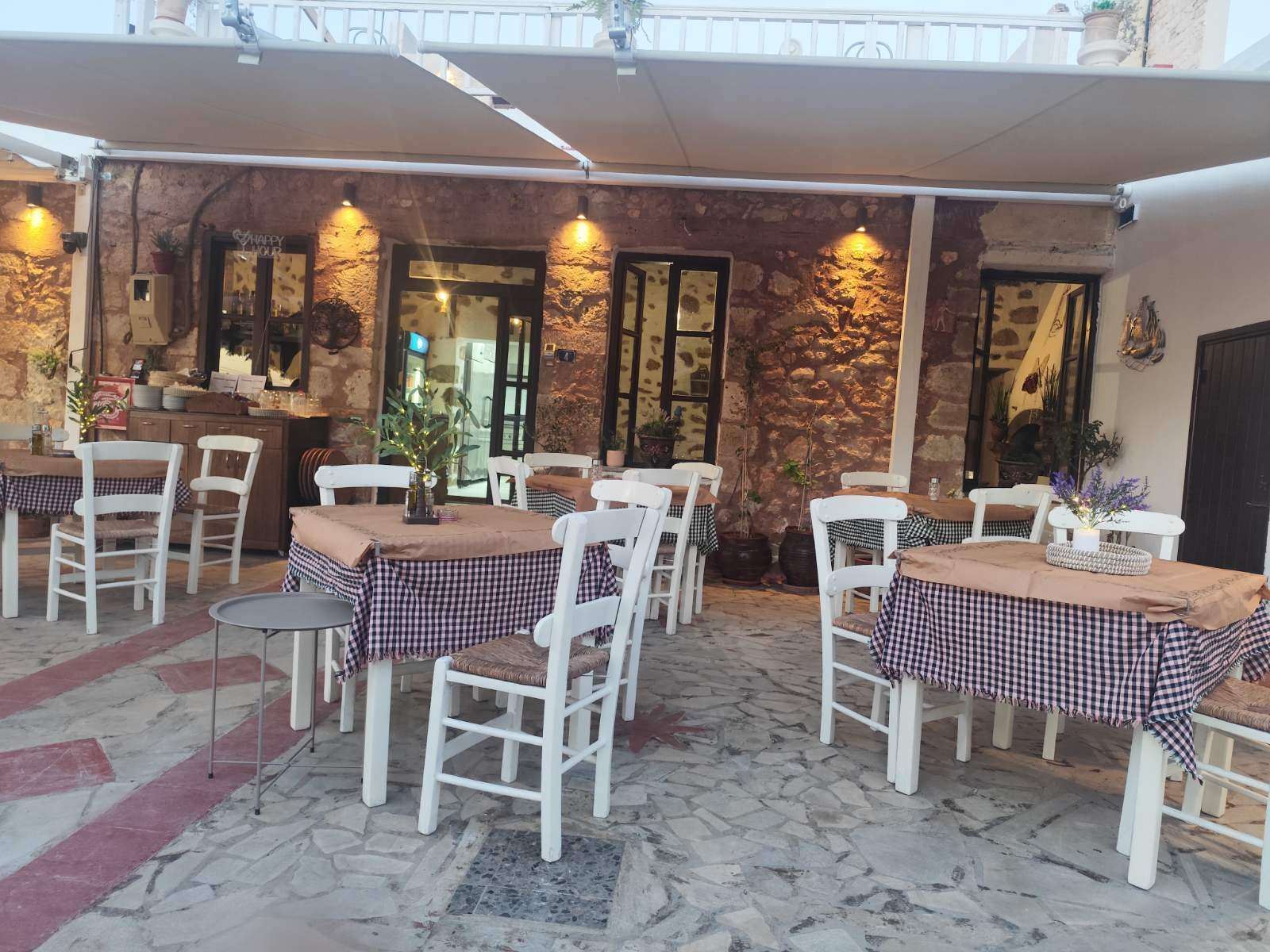 The stone courtyard at rest, checkered tablecloths laid on empty tables.