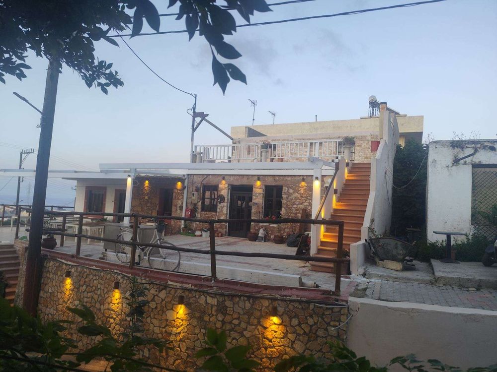 The stone building with lit stairs climbing to the roof terrace.