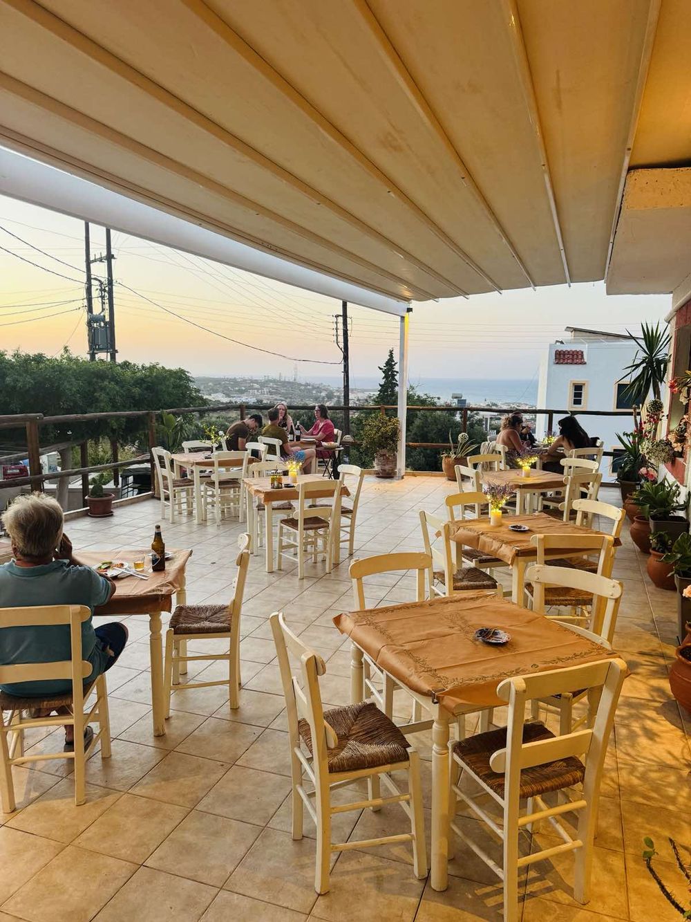 Terrace tables set for the evening, the sea filling the view behind them.